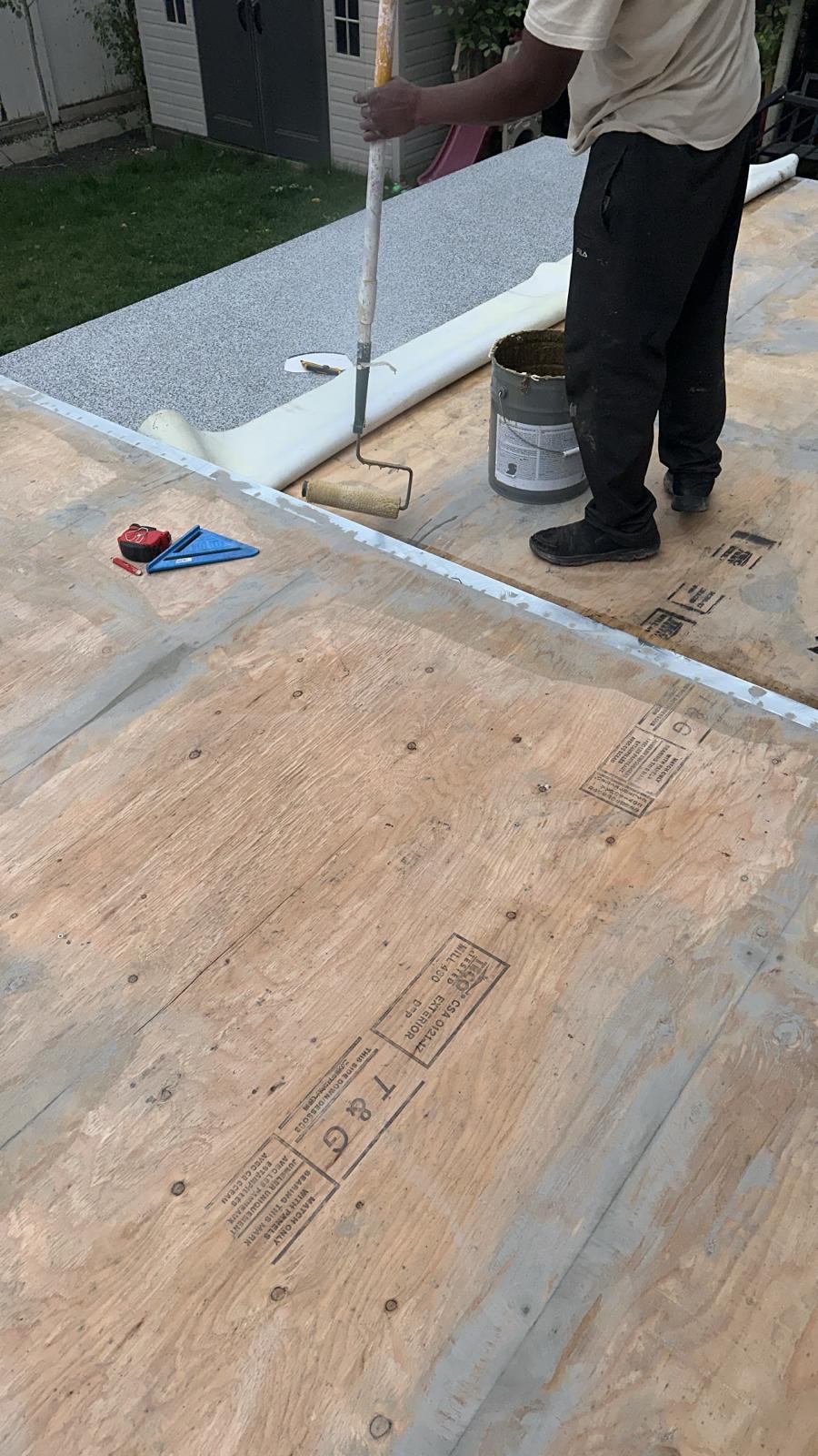 NW Ridge crew member rolling adhesive during a vinyl deck install